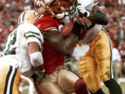 FILE - San Francisco 49ers wide receiver Terrell Owens pulls in a 25-yard touchdown pass from quarterback Steve Young as Green Bay Packers&rsquo; safeties Pat Terrell (40) and Darren Sharper defend late in the fourth quarter of an NFC wild-card NFL football playoff game in San Francisco on Jan. 3, 1999. Owens&rsquo; catch with 3 seconds left in the game led the 49ers to a 30-27 win.