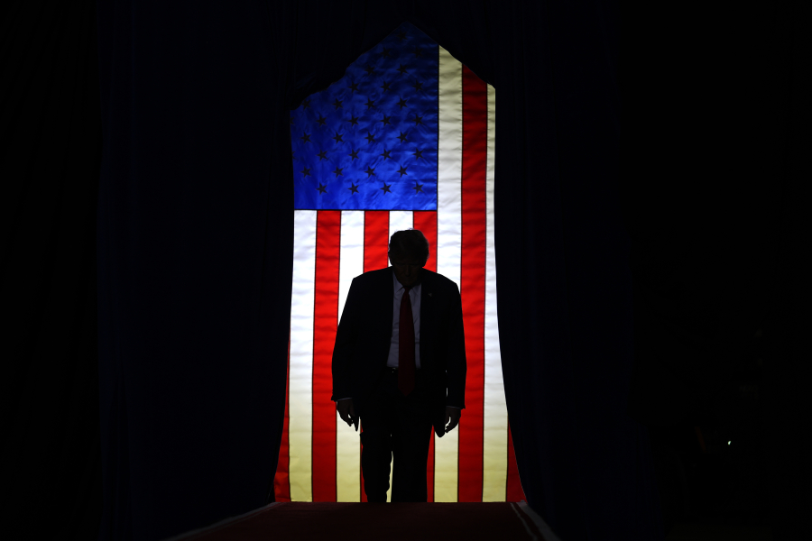 With a U.S. flag in the background, Republican presidential candidate former President Donald Trump steps on stage at a campaign event in Manchester, N.H., Saturday, Jan. 20, 2024.