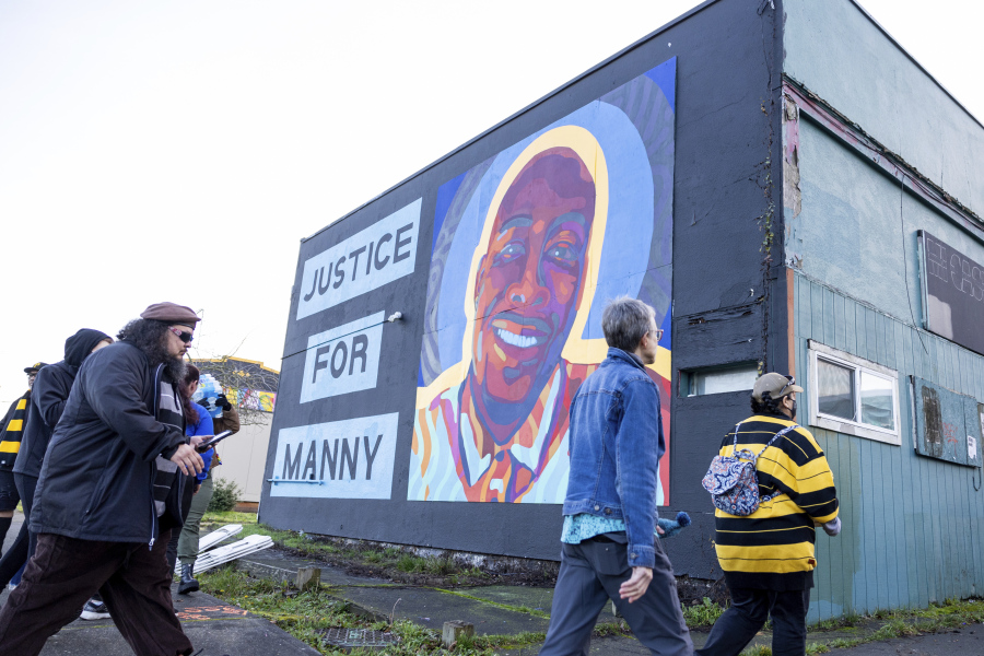 FILE - Protesters walk by a mural of Manny Ellis after the verdict is read during the trial of three Tacoma police officers in the death of Ellis, Dec. 21, 2023, at Pierce County Superior Court in Tacoma, Wash. Three Washington state police officers who were cleared of all criminal charges last month in the 2020 death of Ellis will each receive $500,000 to leave the Tacoma Police Department, according to documents released, Tuesday, Jan. 16, 2024.