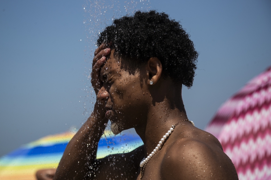 A man cools off in a shower at Ipanema beach in Rio de Janeiro, Brazil, on Sept. 24. Calculations released by several science agencies Friday say that global average temperatures for 2023 shattered existing heat records.