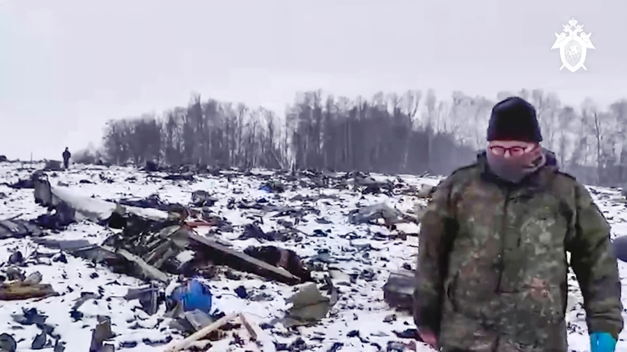 In this image from video released Friday, a Russian Investigative Committee employee walks near wreckage of the Russian military IL-76 plane that crashed near Yablonovo, Russia.