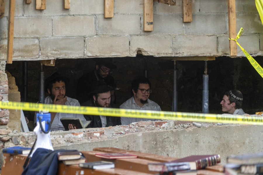 FILE - Hasidic Jewish students sit behind a breach in the wall of a synagogue that led to a tunnel dug by the students, Monday, Jan. 8, 2024, in New York.