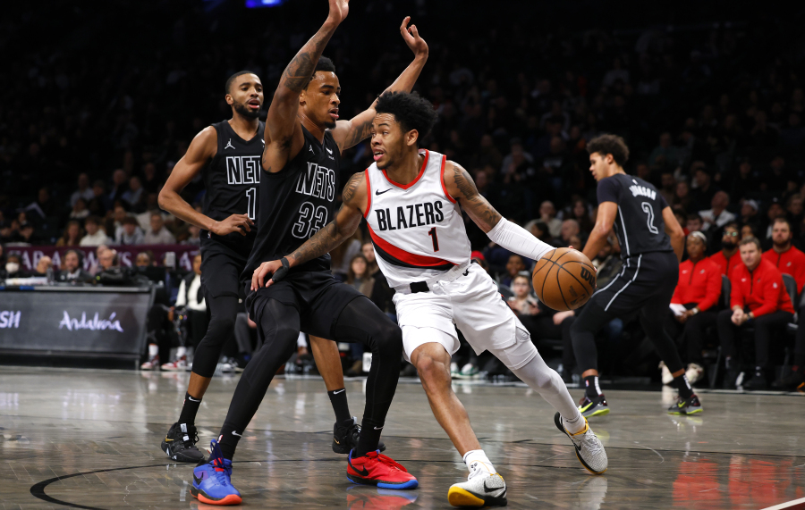 Portland Trail Blazers guard Anfernee Simons, front right, drives the baseline against Brooklyn Nets center Nic Claxton (33) and forward Mikal Bridges, left, during the first half of an NBA basketball game, Sunday, Jan 7, 2024, in New York. (AP Photo/Noah K.