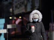 FILE - A pedestrian wears a heavy coat against the cold in New York, Tuesday, Jan. 11, 2022. January can be the worst month for respiratory illnesses and vaccination rates are low. When relatives, friends and co-workers are coming down with coughs, nasal congestion, fatigue and fever, keeping viruses at bay means thorough hand-washing, good ventilation and wearing a mask in crowded areas.