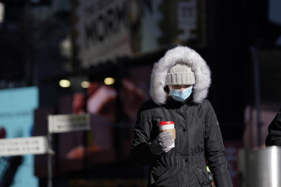 FILE - A pedestrian wears a heavy coat against the cold in New York, Tuesday, Jan. 11, 2022. January can be the worst month for respiratory illnesses and vaccination rates are low. When relatives, friends and co-workers are coming down with coughs, nasal congestion, fatigue and fever, keeping viruses at bay means thorough hand-washing, good ventilation and wearing a mask in crowded areas.