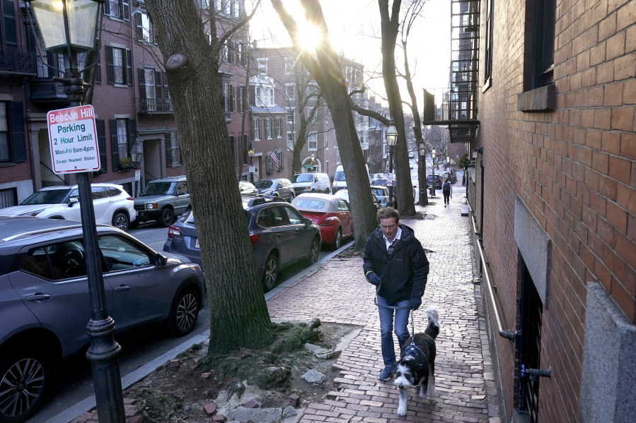 FILE - A passer-by walks their dog in a residential area near the Statehouse on Beacon Hill, Feb. 13, 2023, in Boston. A winter weather system moving through the U.S. is expected to wallop the East Coast this weekend, Saturday, Jan. 6, 2024, into Sunday, Jan. 7, with a mix of snow and freezing rain from the southern Appalachians to the Northeast &mdash; although it&rsquo;s too early to say exactly which areas will get what precipitation and how much.