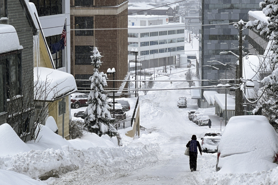 A pedestrian walks down a steep downtown street in Juneau, Alaska, on Tuesday, Jan. 23, 2024. Juneau has received more than 55 inches of snow so far in January, far above the normal level of 24.5 inches, according to the National Weather Service.