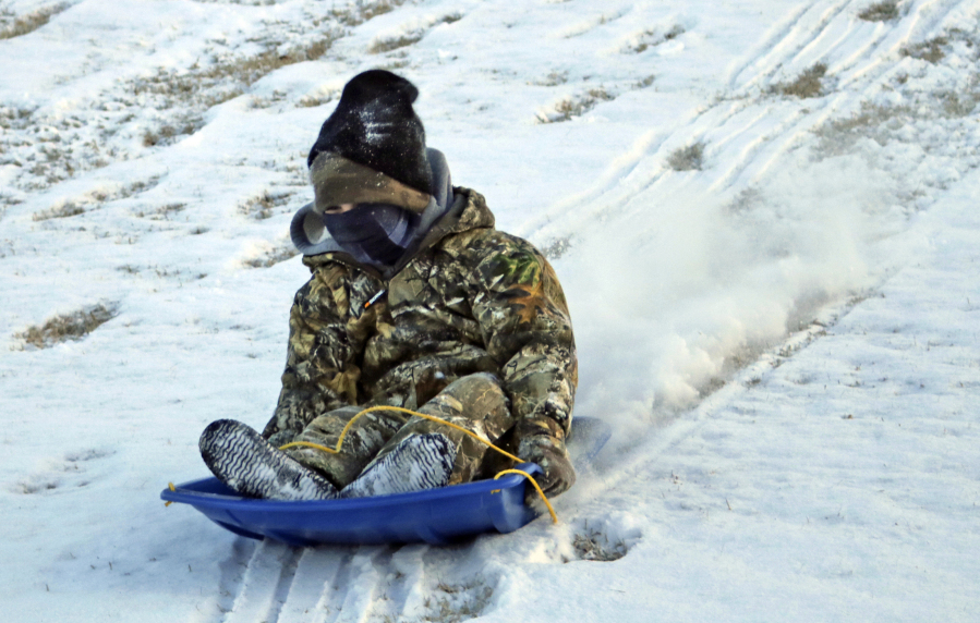 A bundled-up Beau Schilly, 6, sleds down a hill Monday in Jonesboro, Ark. Experts recommend dressing in layers if you must go out in the bitter cold.