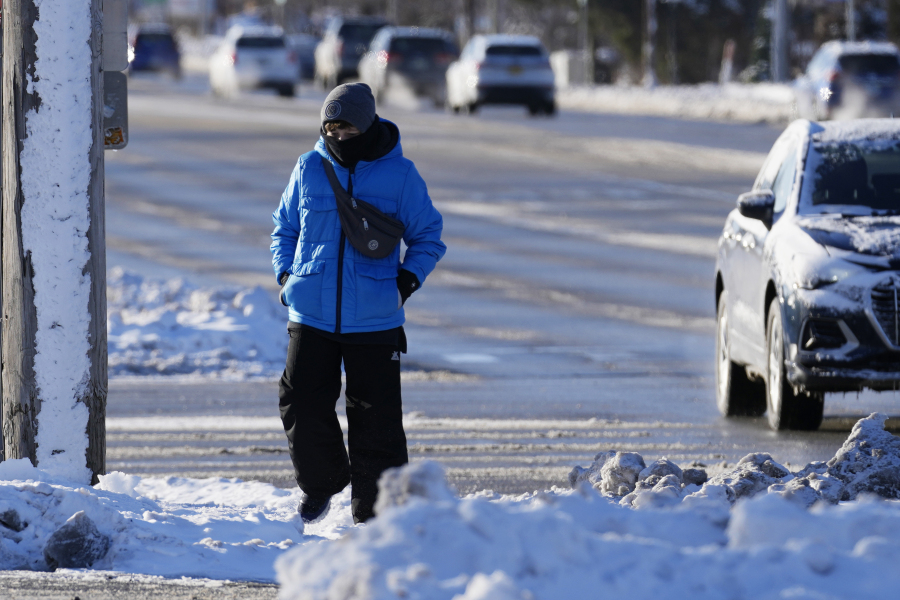 A pedestrian bundles up as she crosses the street in Buffalo Grove, Ill., Sunday, Jan. 14, 2024. A wind chill warning is in effect as dangerous cold conditions continue in the Chicago area. (AP Photo/Nam Y.