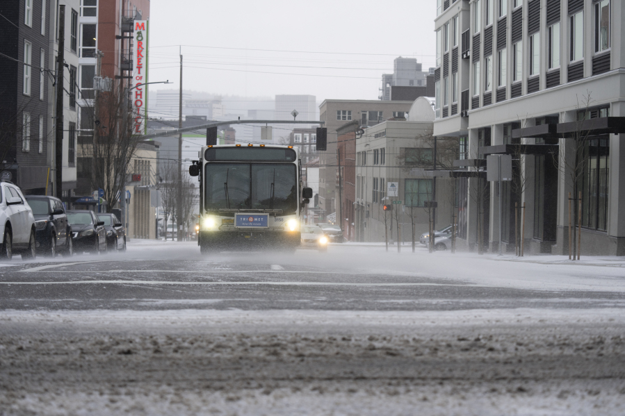 A bus drives on SE Belmont Street in the snow on Saturday, Jan. 13, 2024, in Portland, Ore.