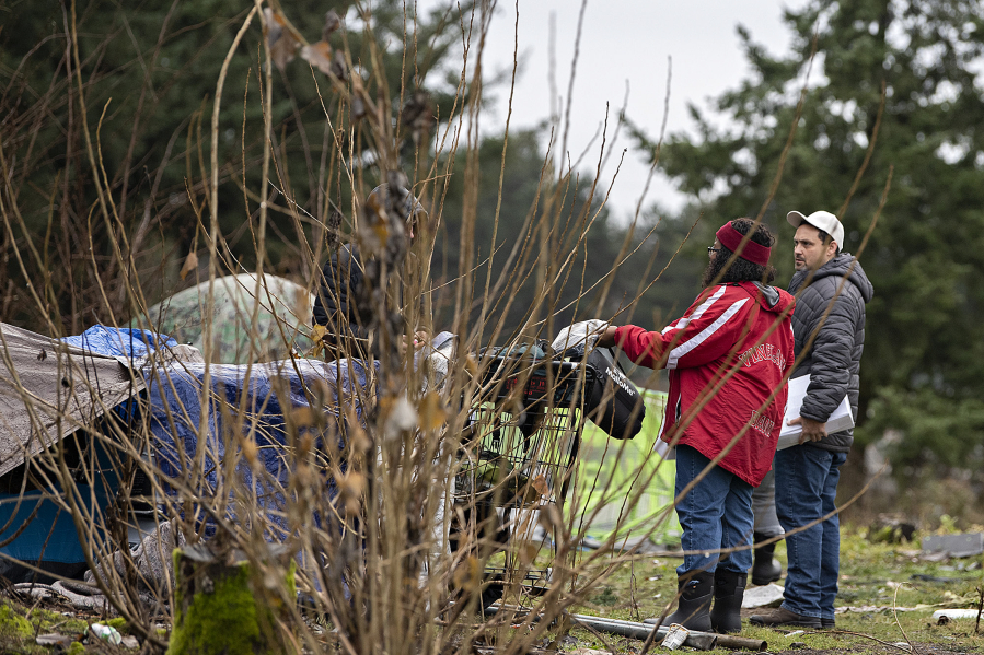 Council for the Homeless outreach team members Magellan Rankin, left, and Brian Starbuck offer supplies to a man at an encampment near Interstate 205 while conducting the Point-in-Time Count Thursday morning.