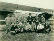 A group poses at the Vancouver Municipal Airport, perhaps sometime around its 1930 dedication. From left to right, the sitting front and standing back rows show Bert Justin, Charles Mears, Freddie Sauers, Art Whitaker, Sid Monastes, an unknown man and Fred Rafferty; and in the rear row: Henry Rasmussen, Ed Klysner, Les Boyd, Edith Foltz, Major Gilbert Eckerson, &igrave;Dad&icirc; Bacon and Lt. Carlton Bond.