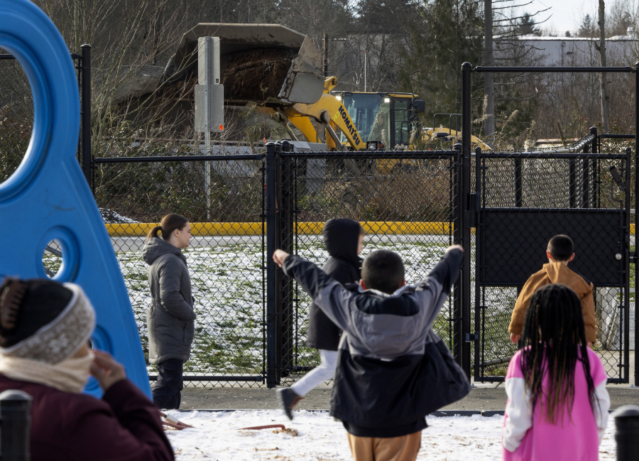A gravel distribution yard operates without a permit across the street from Fairmount Elementary School as students play at recess, Tuesday, Jan. 16, 2024, in Everett, Washington.