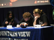 Mountain View seniors Aiden Nicholson (center) and Cash Cook sign papers during a College Signing Day ceremony at Mountain View High School on Wednesday, Feb. 7, 2024.