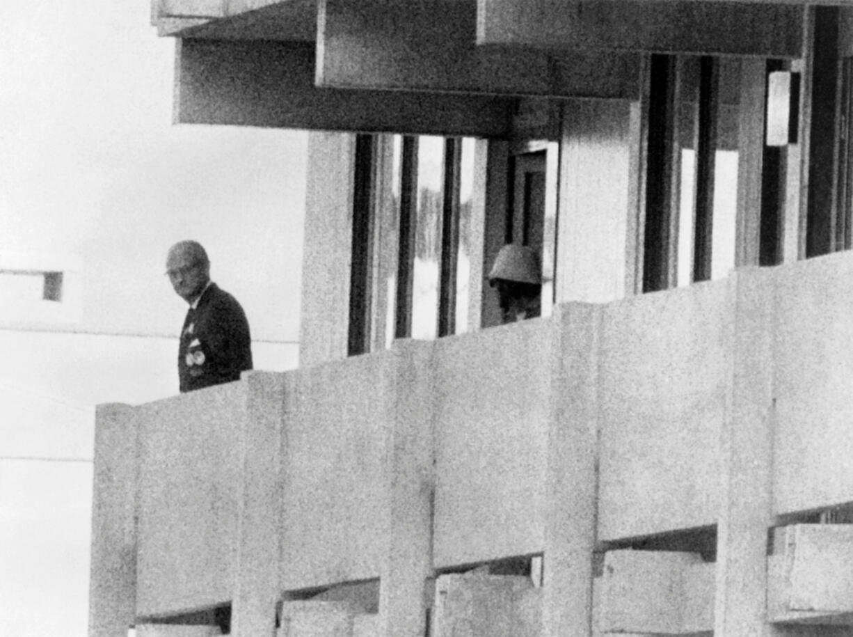 A member of the Palestinian militant organization Black September, which seized members of the Israeli Olympic team at their quarters in the Olympic Village, watches an official, at left, on the building&rsquo;s balcony on Sept. 5, 1972, in Munich.