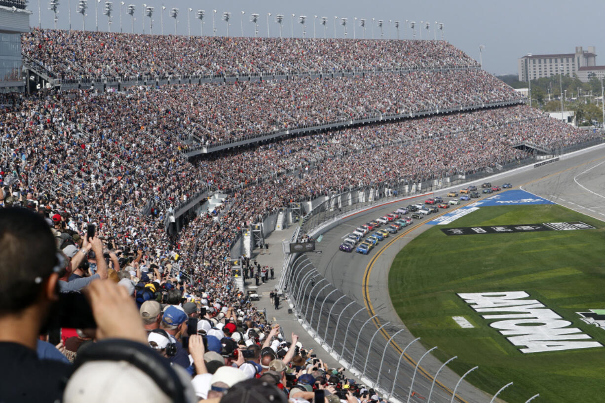 FILE - A sold out crowd watches as Alex Bowman, front left, and Kyle Larson, front right, lead the field to start the NASCAR Daytona 500 auto race at Daytona International Speedway, Sunday, Feb. 19, 2023, in Daytona Beach, Fla. A new NASCAR season begins with rivals attempting to dethrone Team Penske after two years atop the Cup Series, all while a compelling off-track battle rages on over revenue sharing that threatens to overshadow the competition.