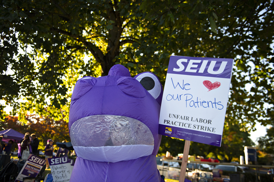An inflatable purple dinosaur shows support for patients as Kaiser Permanente workers strike in front of the Cascade Park clinic on Oct. 6, 2023. Workers who are on strike or locked out of their workplace by their employer due to a labor dispute would gain access to unemployment insurance benefits under a bill the Washington state House approved in the early morning hours Tuesday, Feb. 13, 2024.