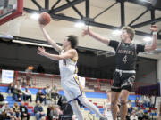 Columbia River’s John Reeder, left, soars past W.F. West’s Gage Brumfield for a layup during a Class 2A District 4 boys basketball semifinal game on Tuesday, Feb. 13, 2024, at Mark Morris High School.