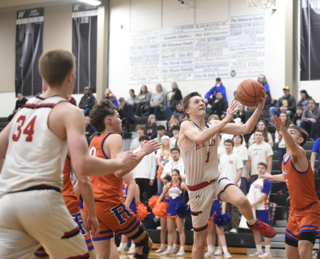 R.A. Long’s Payton Thill (1) goes up for a layup against Ridgefield defenders during a Class 2A District 4 winner-to-state boys basketball game on Thursday, Feb. 15, 2024, at Woodland High School.