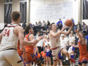 R.A. Long’s Payton Thill (1) goes up for a layup against Ridgefield defenders during a Class 2A District 4 winner-to-state boys basketball game on Thursday, Feb. 15, 2024, at Woodland High School.