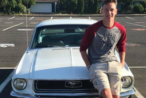 Washougal High School graduate Alec Langen poses for a photograph with his car in his school parking space in 2018.
