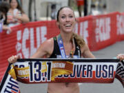 Sarah Crouch holds up the finish line banner after winning a half marathon on June 21, 2015 in Vancouver. The former standout runner at Western Washington University and Hockinson High alum will be going into the WWU athletics hall of fame, the school announced Thursday, Feb. 29, 2024.