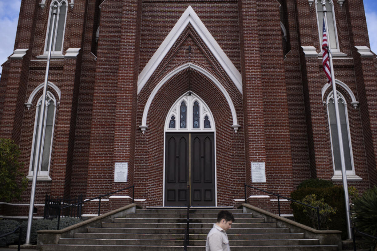 Robert Pinedo, who lives and works in Vancouver, strolls past the Proto-Cathedral of St. James the Greater during his lunch break. The Archdiocese of Seattle announced its final plans to consolidate its 136 parishes into just 60 parish families.