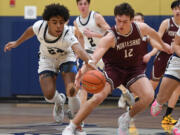 Seton Catholic freshman Kaiden Wilson, left, and Montesano senior Gabe Bodwell fight for a loose ball Friday, Feb. 9, 2024, during the Cougars’ 58-46 win against Montesano at Seton Catholic High School.