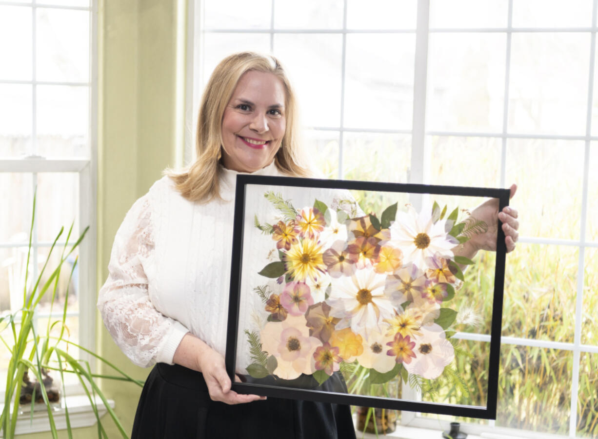 Daphne Andersons holds a completed, framed bouquet. Her business, Vancuterie, offers bridal bouquet preservation using ancient Japanese flower-pressing techniques.