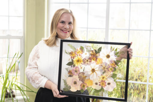 Daphne Andersons holds a completed, framed bouquet. Her business, Vancuterie, offers bridal bouquet preservation using ancient Japanese flower-pressing techniques. (Photos by Taylor Balkom/The Columbian)