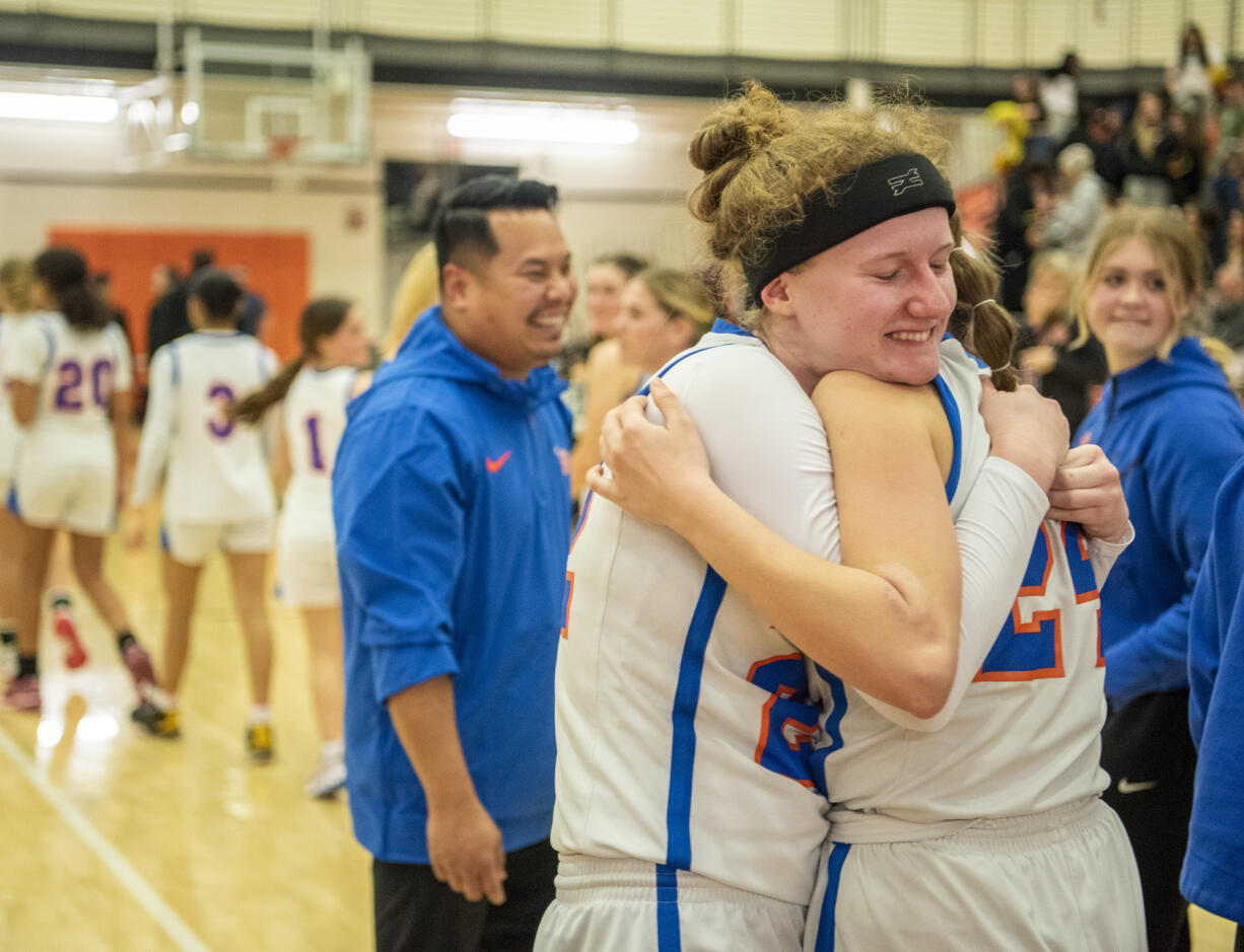Ridgefield senior Elizabeth Swift, left, hugs senior Morgan Goode on Friday, Feb. 23, 2024, after the Spudders’ 59-46 win against Kingston in a 2A Opening Round game at Battle Ground High School.