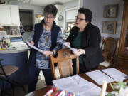 Jayne McCarley, left, a resident of Meadow Verde Mobile Home Park, looks over paperwork including her rent increase notice with fellow resident Michelle Bart at her Hazel Dell home Monday morning hours before they knew a rent stabilization bill would die.