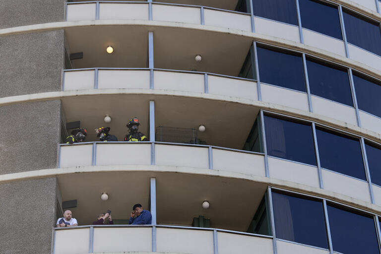 People and firefighters in Smith Tower look out from balconies during a two-alarm fire downtown Friday morning, Feb. 23, 2024.