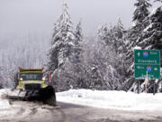 FILE - In this Dec. 22, 2015, file photo, a snowplow clears an overpass of freshly fallen snow over Interstate 90 at Snoqualmie Pass.
