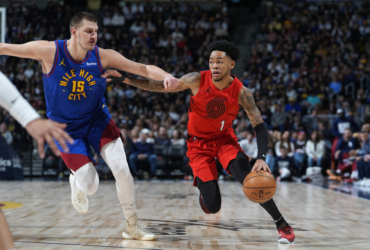 Portland Trail Blazers guard Anfernee Simons, right, drives past Denver Nuggets center Nikola Jokic in the first half of an NBA basketball game Friday, Feb. 2, 2024, in Denver.