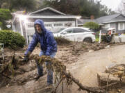 Jeffrey Raines clears debris from a mudslide at his parent's home during a rainstorm, Monday, Feb. 5, 2024, in Los Angeles. The second of back-to-back atmospheric rivers took aim at Southern California, unleashing mudslides, flooding roadways and knocking out power as the soggy state braced for another day of heavy rains.