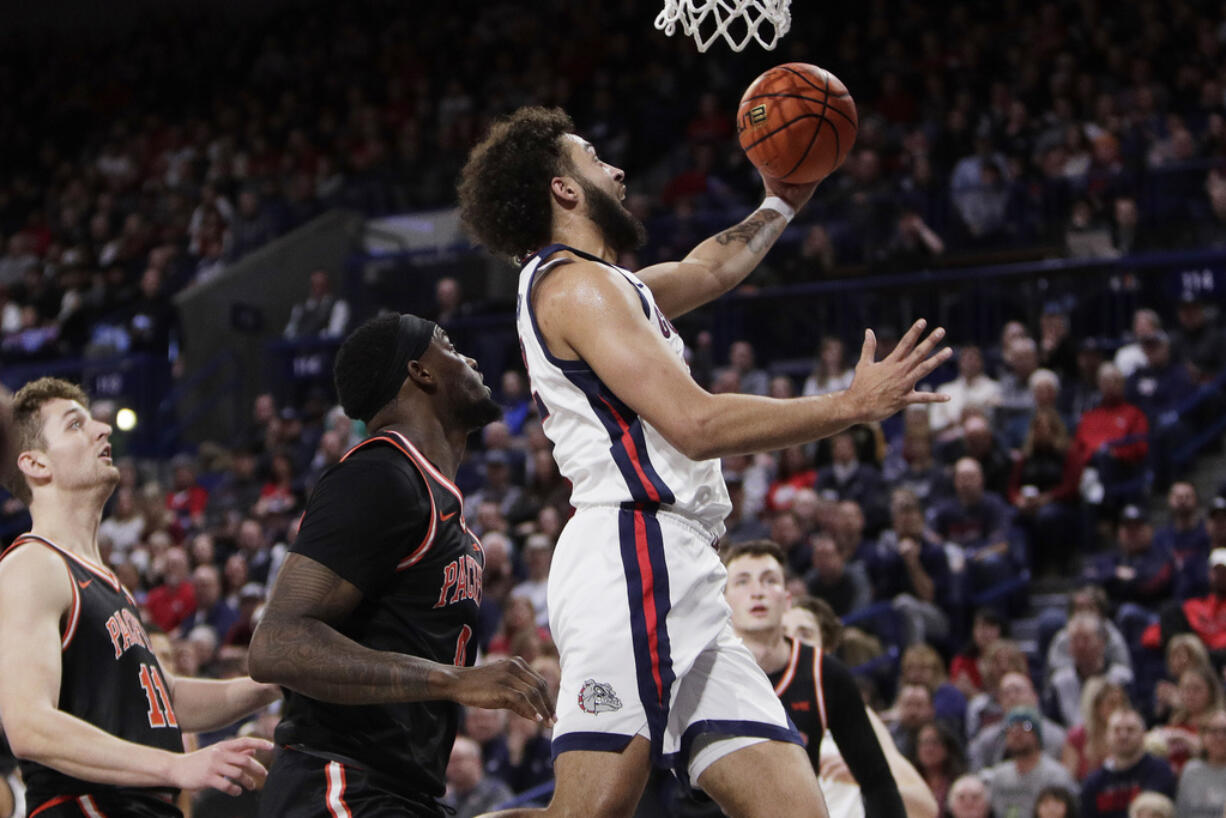 Gonzaga forward Anton Watson, center, drives to the basket next to Pacific guard Greg Outlaw during the first half of an NCAA college basketball game, Saturday, Feb. 17, 2024, in Spokane, Wash.