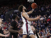 Gonzaga forward Anton Watson, center, drives to the basket next to Pacific guard Greg Outlaw during the first half of an NCAA college basketball game, Saturday, Feb. 17, 2024, in Spokane, Wash.