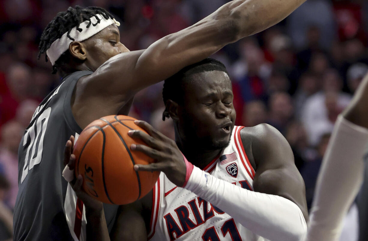 Washington State center Rueben Chinyelu (20) defends against Arizona center Oumar Ballo (11) under the basket during the first half of an NCAA college basketball game Thursday, Feb. 22, 2024, in Tucson, Ariz.