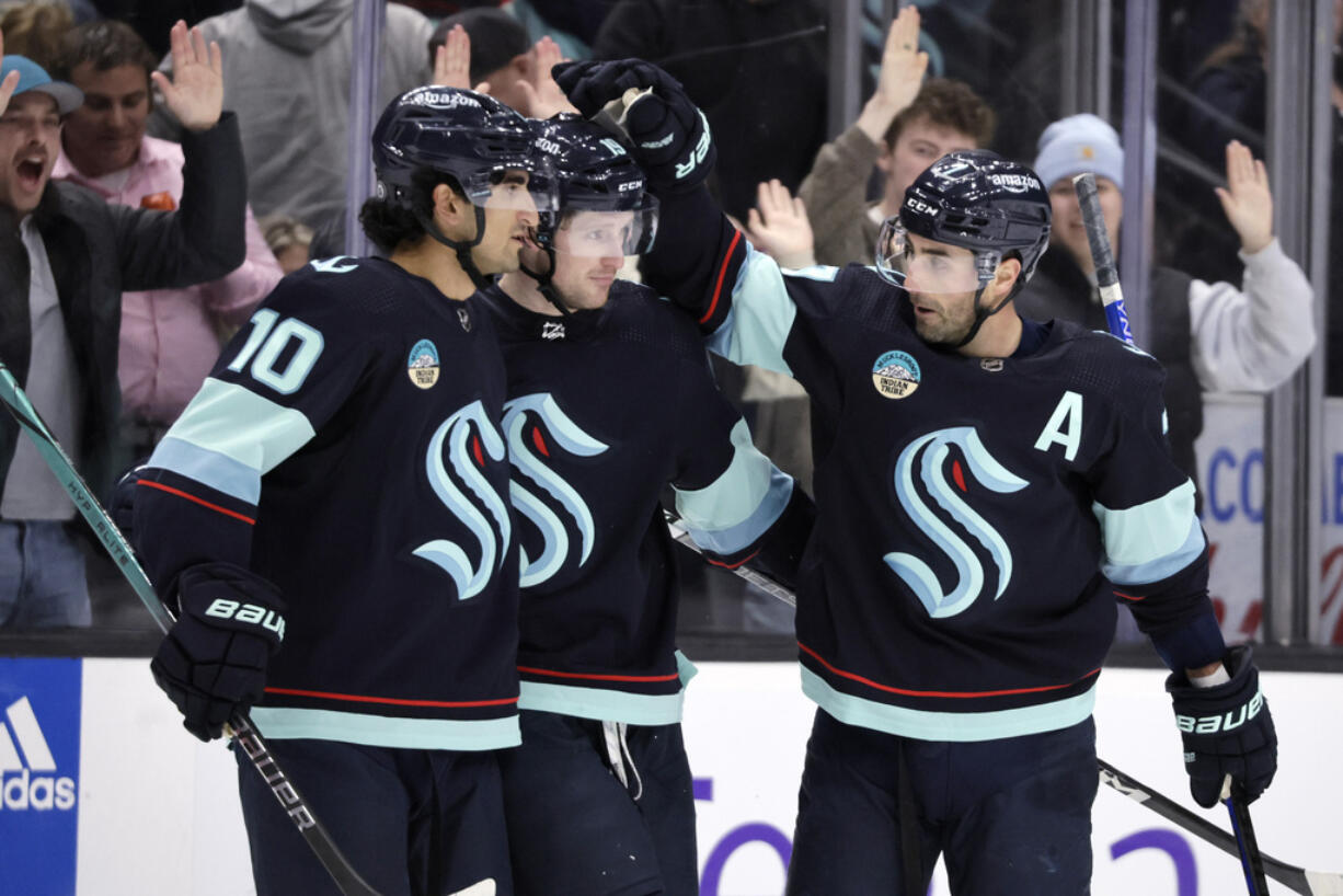 Seattle Kraken right wing Jordan Eberle, right, celebrates his goal against the Vancouver Canucks with left wing Jared McCann, center, and center Matty Beniers, left, during the third period of an NHL hockey game Thursday, Feb. 22, 2024, in Seattle.