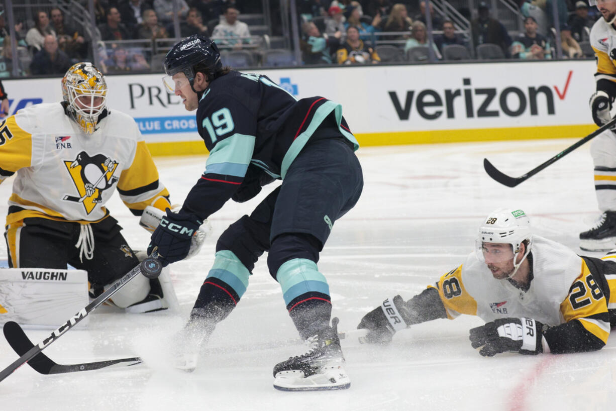 Seattle Kraken left wing Jared McCann (19) attempts to score against Pittsburgh Penguins goaltender Tristan Jarry, left, as Penguins defenseman Marcus Pettersson (28) defends during the first period of an NHL hockey game Thursday, Feb. 29, 2024, in Seattle.