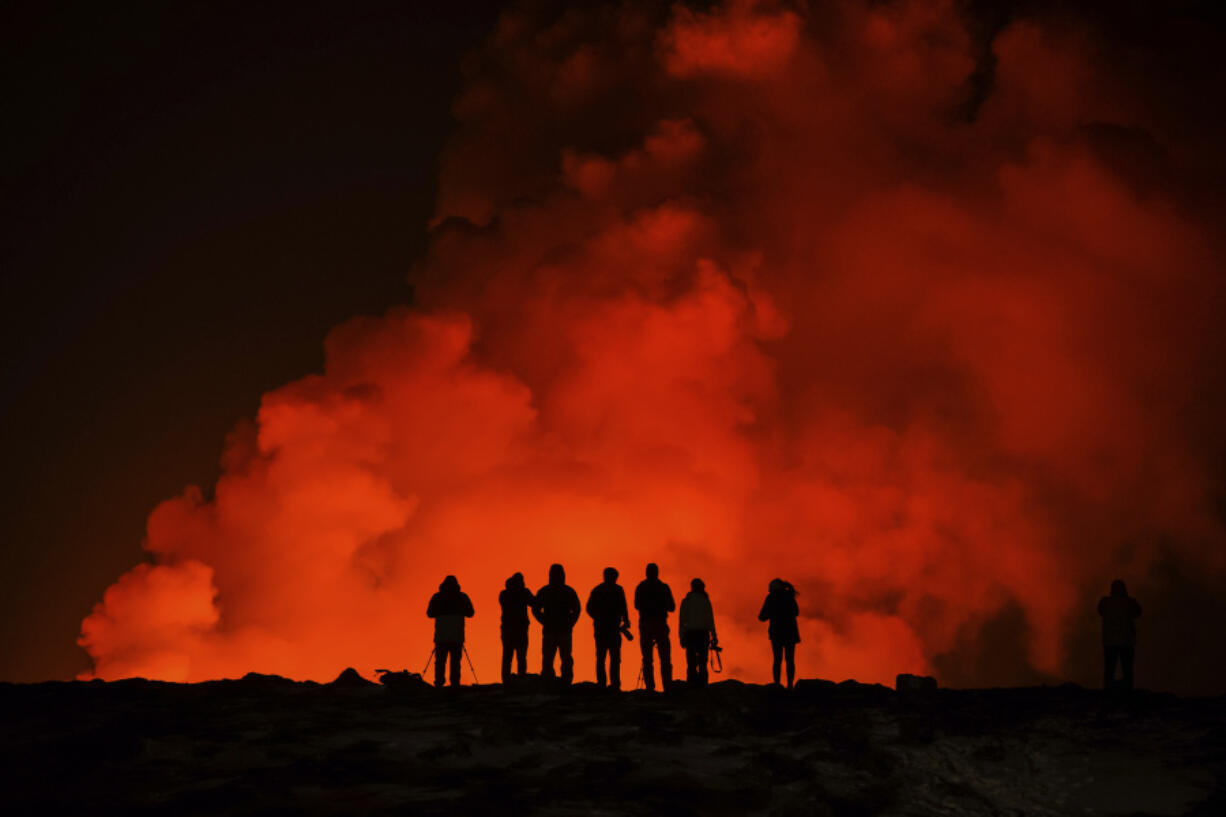 People look at the volcano erupting, north of Grindav&iacute;k, Iceland, Thursday, Feb. 8, 2024. Iceland&rsquo;s Meteorological Office says a volcano is erupting in the southwestern part of the country, north of a nearby settlement. The eruption of the Sylingarfell volcano began at 6 a.m. local time on Thursday, soon after an intense burst of seismic activity.