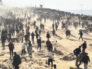 Palestinians wait for humanitarian aid on a beachfront in Gaza City, Gaza Strip, Sunday, Feb. 25, 2024.