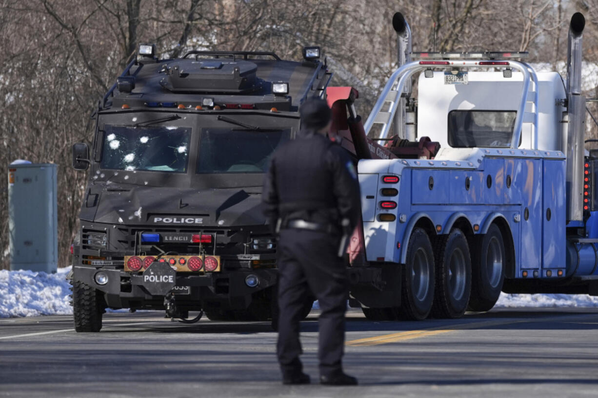 A police vehicle with what appears to be bullet pockmarks is towed near the scene where two police officers and a first responder were shot and killed Sunday, Feb. 18, 2024, in Burnsville, Minn.