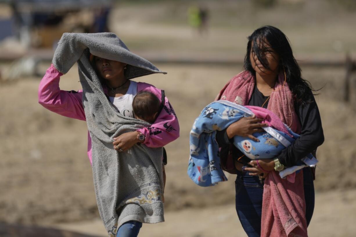 Women carry babies after arriving by boat from La Bulla Loca mine, which collapsed, in La Paragua, Bolivar state, Venezuela, Friday, Feb. 23, 2024. The collapse of the illegally operated open-pit gold mine in a remote area of central Venezuela killed at least 16 people.