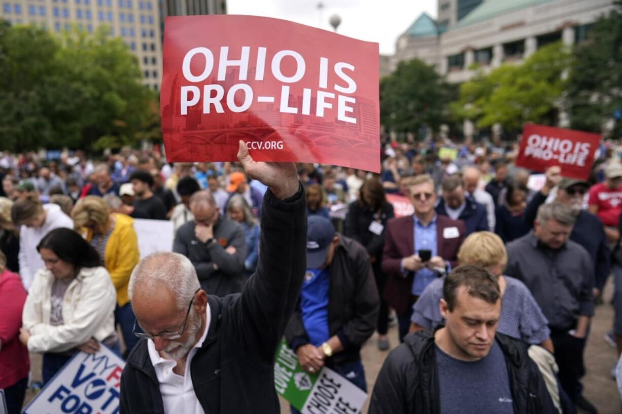 FILE - Paul Meacham holds high a sign that reads &ldquo;Ohio is pro-life&rdquo; as the crowd prays during the Ohio March for Life rally at the Ohio State House in Columbus, Ohio, Friday, Oct. 6, 2023.  Abortion questions are already on the ballot for 2024 in two states and could also appear in several others.