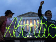 FILE - Activists mark the first anniversary of the Supreme Court&rsquo;s decision in Dobbs v. Jackson Women&rsquo;s Health Organization, by displaying neon signage in support of abortion access in front of the Supreme Court on June 23, 2023, in Washington.  A report finds the total number of monthly abortions in the U.S. increased after state bans started kicking in in 2022.