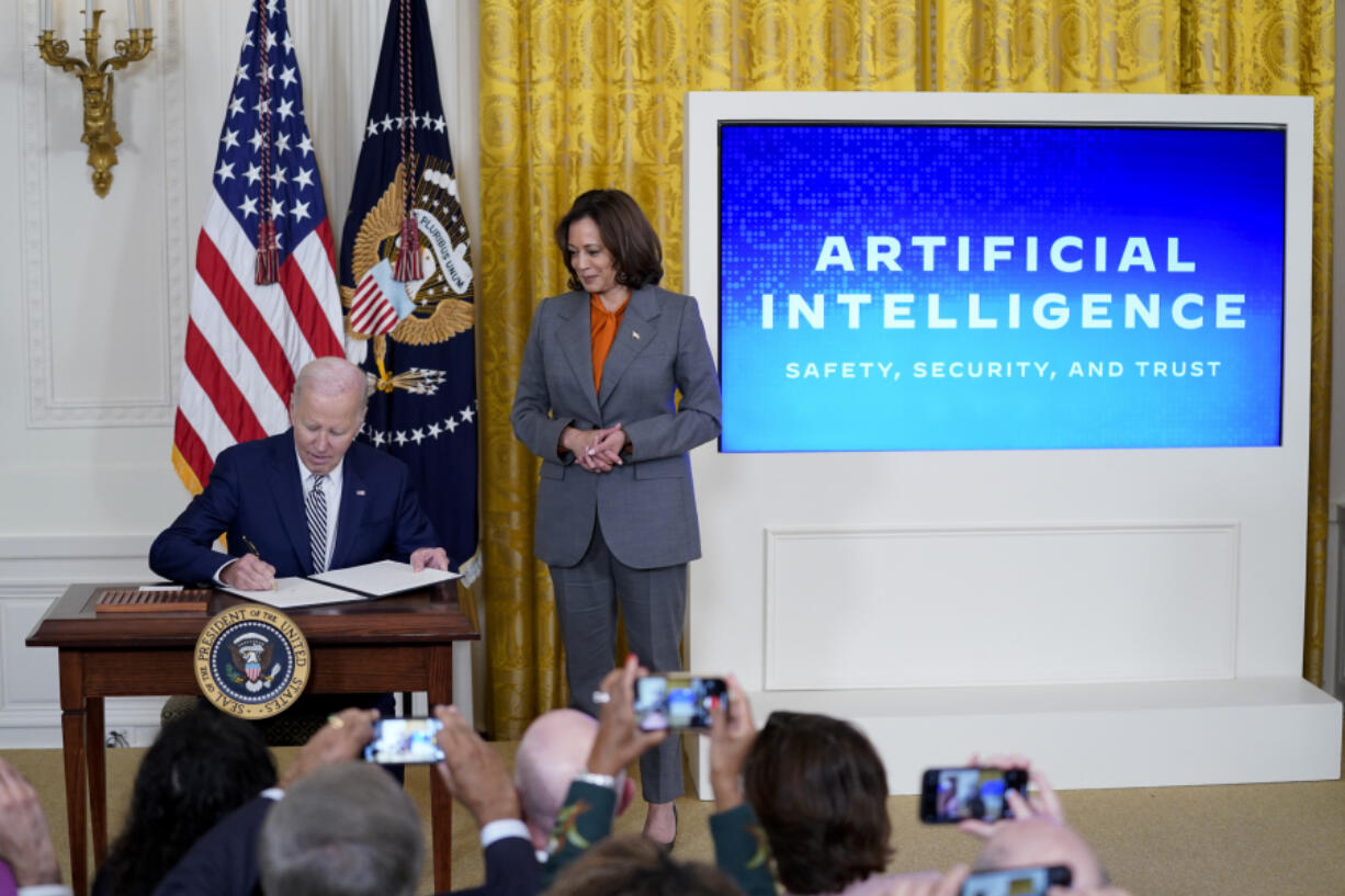 FILE - President Joe Biden signs an executive on artificial intelligence in the East Room of the White House, Oct. 30, 2023, in Washington. Vice President Kamala Harris looks on at right. The White House said Wednesday, Feb. 21, 2024, that it is seeking public comment on the risks and benefits of having an AI system&rsquo;s key components publicly available for anyone to use and modify.