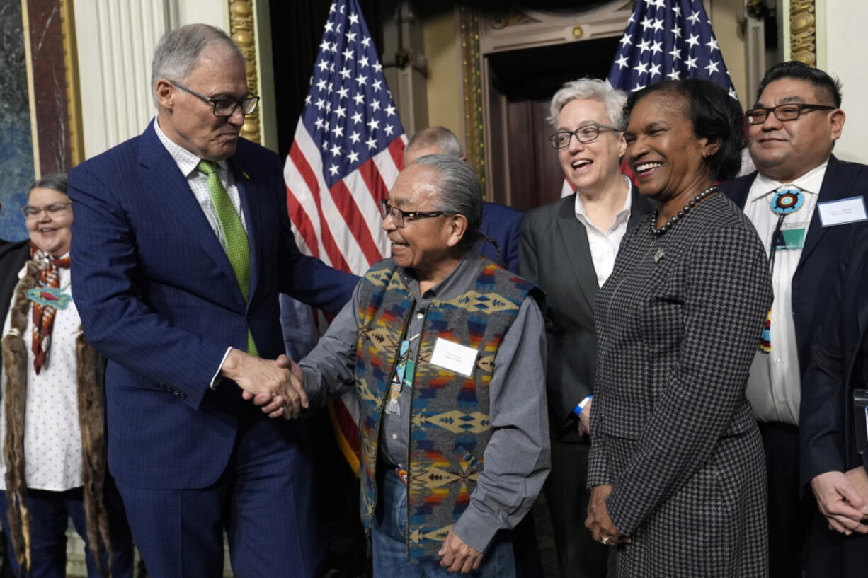 Washington Gov. Jay Inslee, left, shakes hands with Chair Gerry Lewis of the Yakama Nation, following a ceremonial signing ceremony in Washington, Friday, Feb. 23, 2024, as Oregon Gov. Tina Kotek, third from right, Chair of the Council on Environmental Quality Brenda Mallory, second from right, and Chair Shannon Wheeler of the Nez Perce Tribe, right, watch. The ceremonial signing is an agreement between the Biden administration and state and Tribal governments to work together to protect salmon and other native fish, honor obligations to Tribal nations, and recognize the important services the Columbia River System provides to the economy of the Pacific Northwest.
