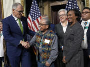 Washington Gov. Jay Inslee, left, shakes hands with Chair Gerry Lewis of the Yakama Nation, following a ceremonial signing ceremony in Washington, Friday, Feb. 23, 2024, as Oregon Gov. Tina Kotek, third from right, Chair of the Council on Environmental Quality Brenda Mallory, second from right, and Chair Shannon Wheeler of the Nez Perce Tribe, right, watch. The ceremonial signing is an agreement between the Biden administration and state and Tribal governments to work together to protect salmon and other native fish, honor obligations to Tribal nations, and recognize the important services the Columbia River System provides to the economy of the Pacific Northwest.